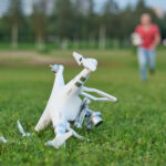 Crashed quadrocopter in park. Propeller damage. Operator running on the background